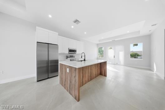 Kitchen with brown cabinets, stainless steel appliances, white cabinets, finished concrete floors, and recessed lighting