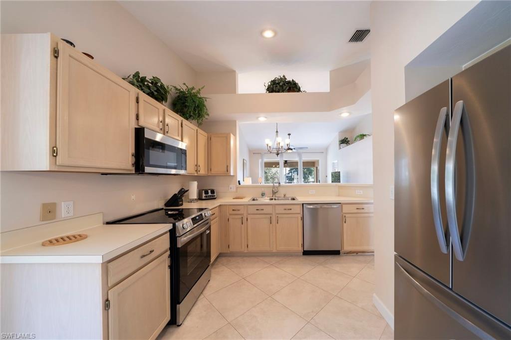Kitchen featuring light brown cabinets, stainless steel appliances, light countertops, a chandelier, and recessed lighting