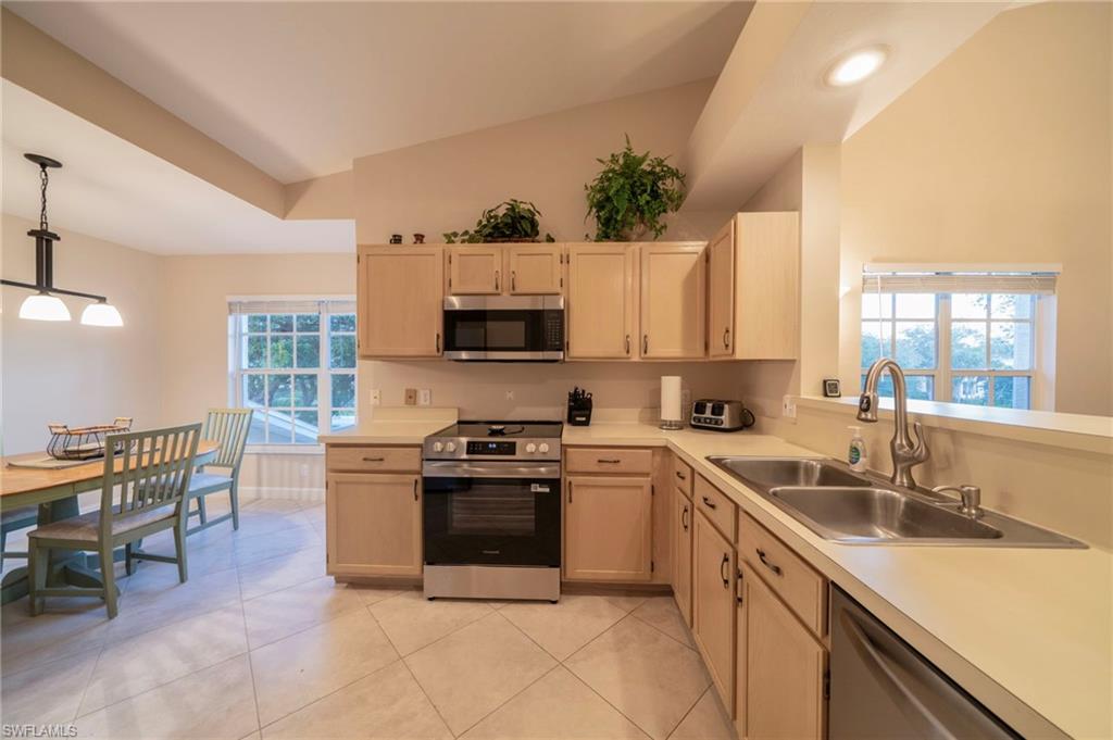 Kitchen with light brown cabinets, appliances with stainless steel finishes, and vaulted ceiling
