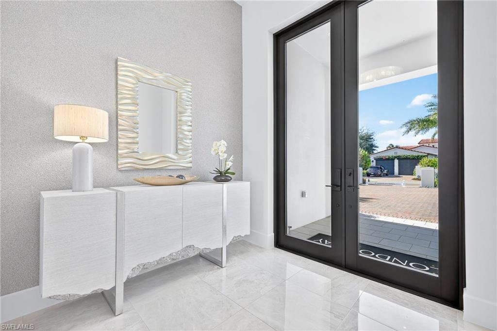 Bright, modern entry with a clean, coastal-inspired aesthetic features large modern double doors with full-height glass panels allows lots of natural light