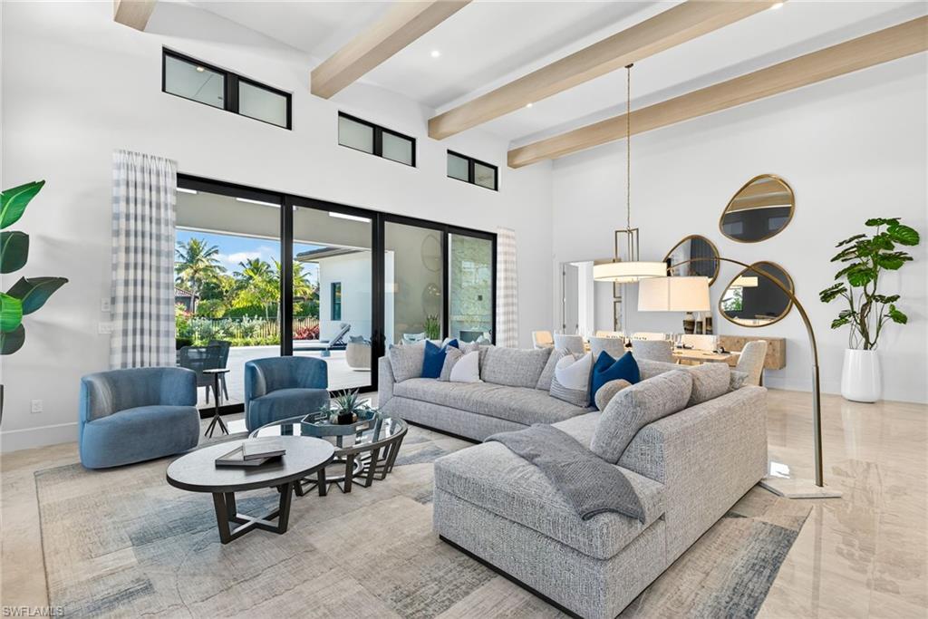 Living room featuring soaring 16 ft ceilings with gorgeous beams, plenty of natural lighting from the floor to ceiling doors