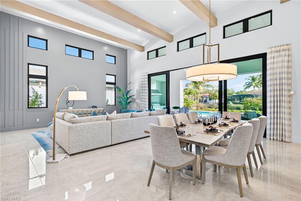 This stunning open-concept great room showcases soaring ceilings with elegant wood beams and an abundance of natural light streaming through