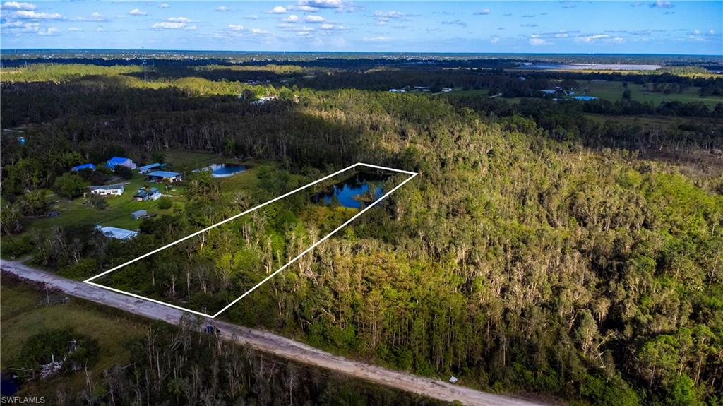 Aerial view of property and surrounding area featuring property boundaries highlighted and a large body of water