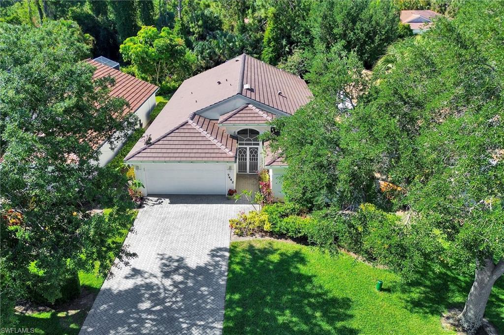 Exterior featuring a tiled roof, arched entry, paver driveway, and a two-car garage