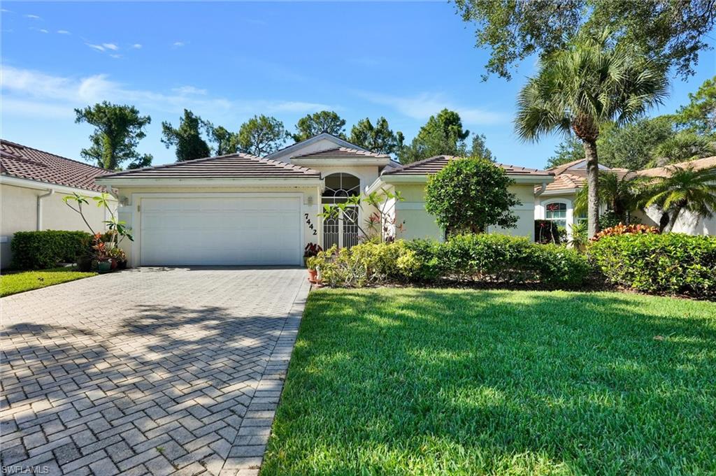 Single-story residence featuring a tile roof, a two-car garage, and a paver driveway