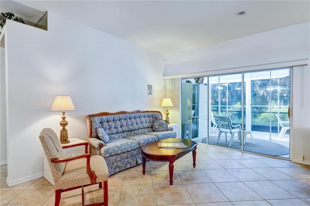 Living area featuring large format tile flooring, white walls, and sliding glass doors leading to an outdoor patio