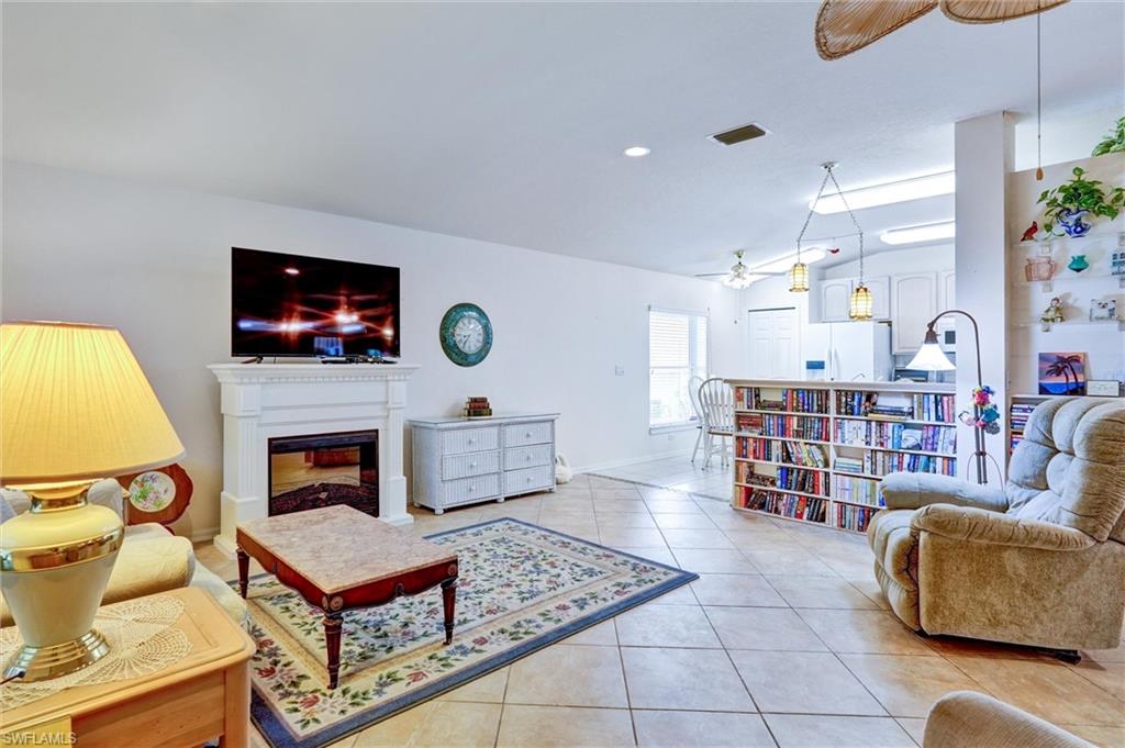 Spacious living area featuring tile flooring, a built-in electric fireplace with a white mantel, and recessed lighting