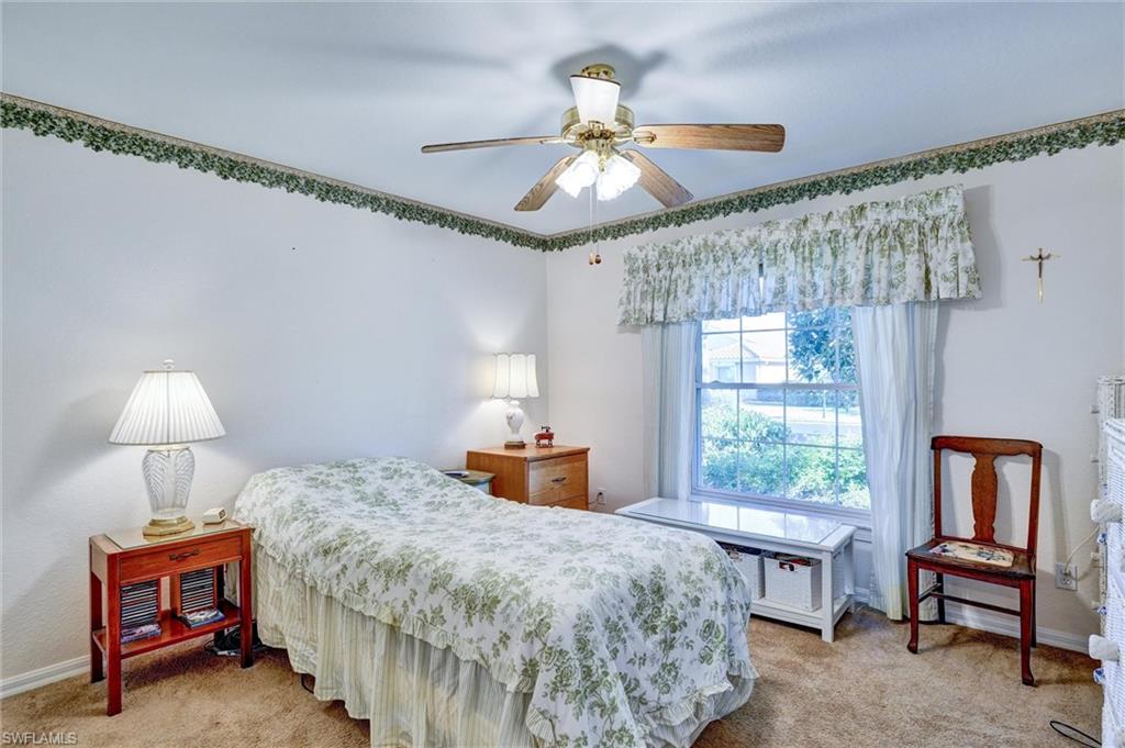 Carpeted room with a ceiling fan, a window with a valance, and a decorative border along the wall