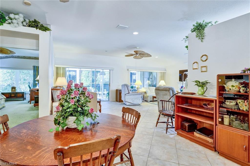 Open-concept living area featuring light-toned tile flooring, recessed lighting, and ceiling fans
