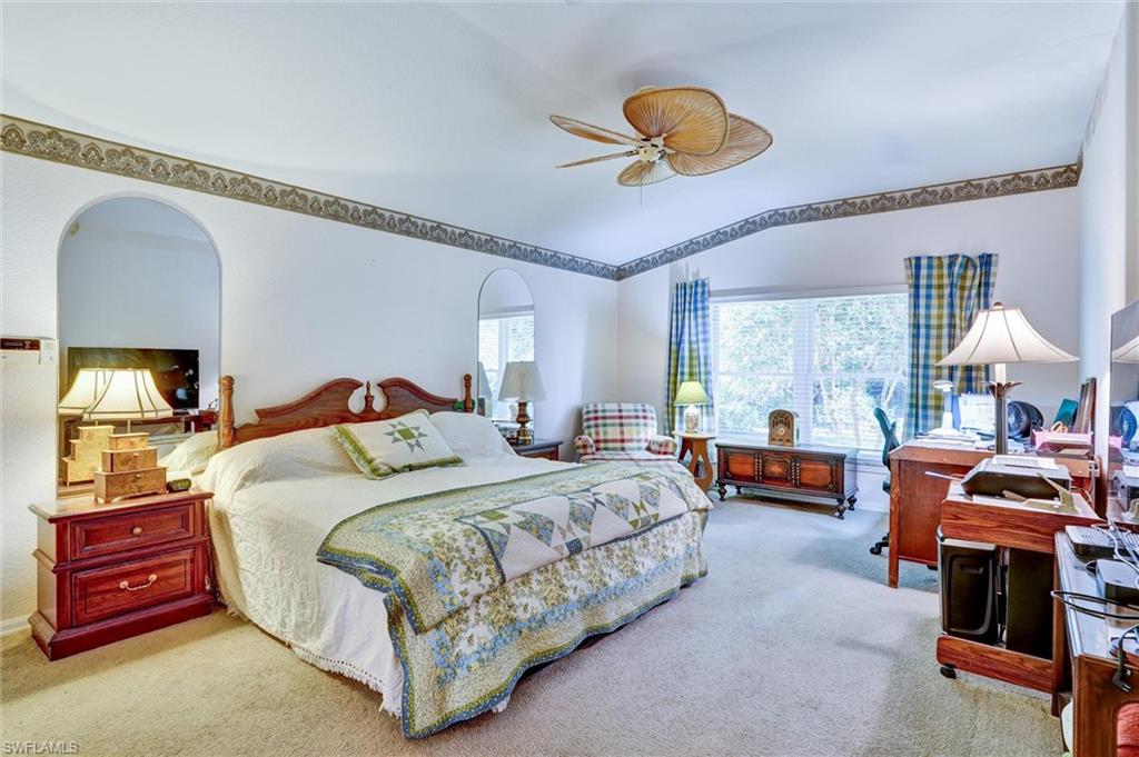 Carpeted room with a ceiling fan, a large window, and wall archways
