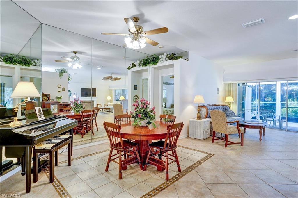 Spacious interior featuring large format tile flooring with decorative mosaic inlay, a full-wall mirrored accent, and ceiling fans