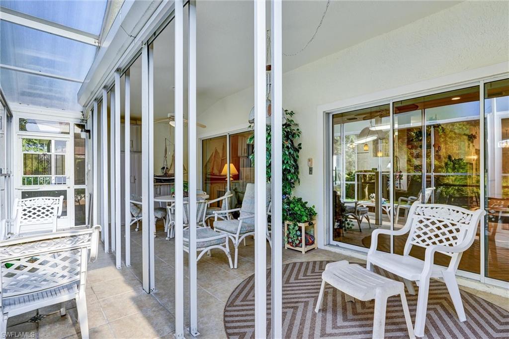 Screened patio featuring a translucent roof, multiple sliding glass doors, tile flooring, and white vertical framing