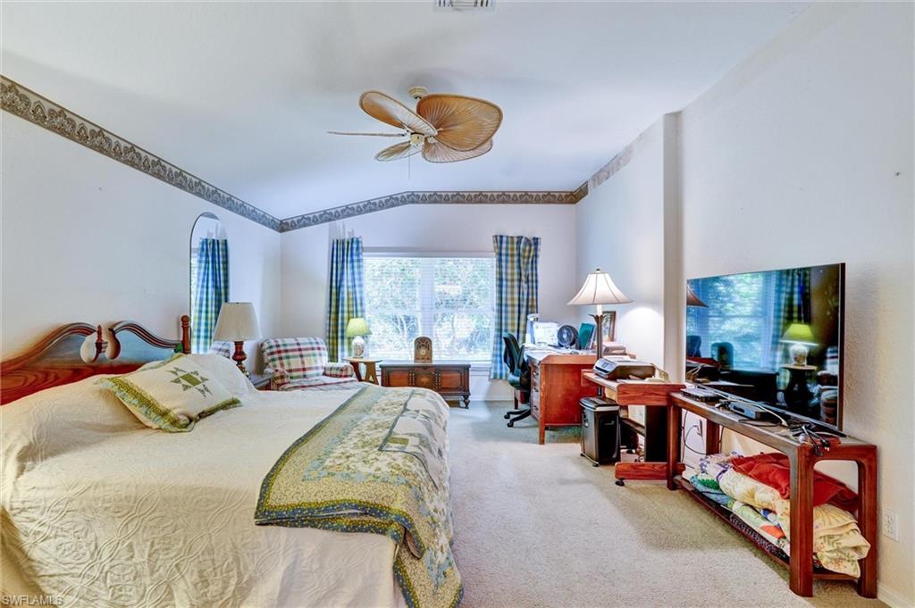 Spacious interior room featuring vaulted ceilings, a ceiling fan, and carpet flooring
