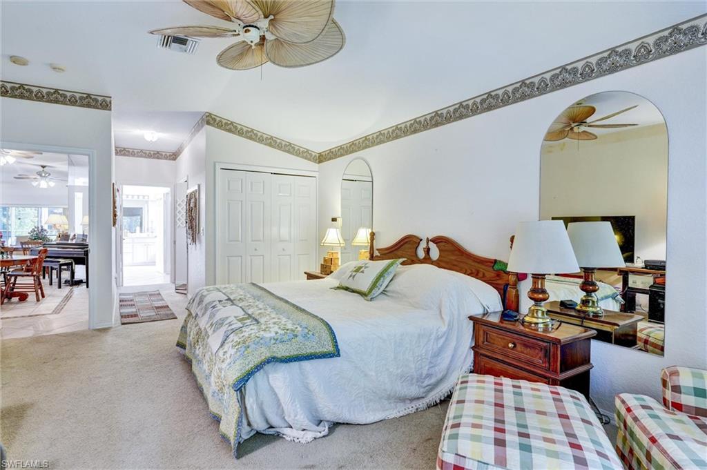 Bedroom featuring wall-to-wall carpeting, dual bi-fold closet doors, and arched wall mirrors