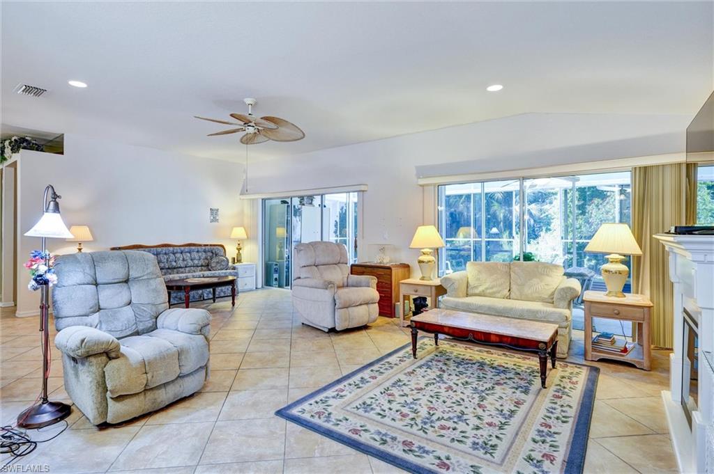 Spacious living area featuring neutral-toned tile flooring, a sloped ceiling, and recessed lighting
