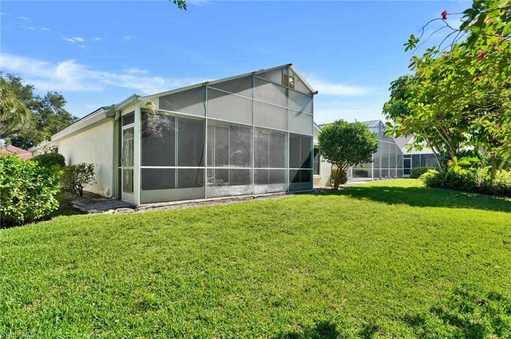 Expansive green lawn bordering a screened enclosure with a peaked roofline