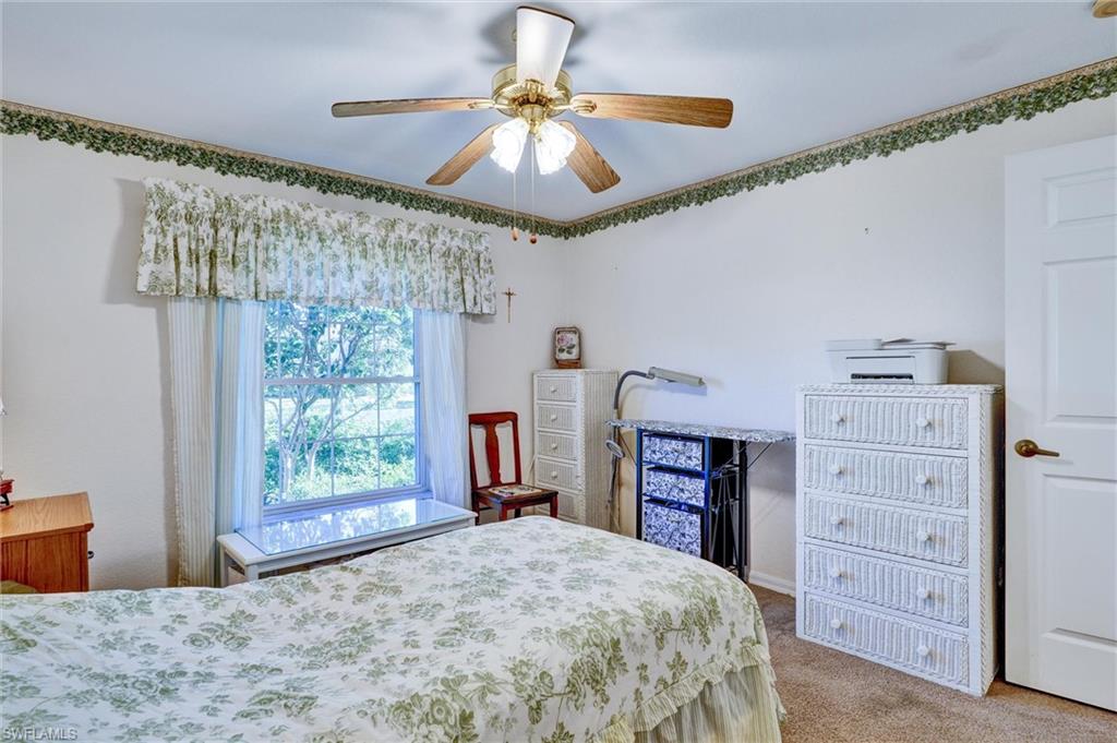 Carpeted room featuring a ceiling fan with integrated lighting, a window with a valance, and a white paneled door