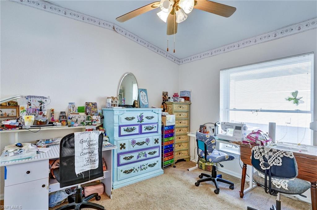 Carpeted room featuring a ceiling fan with integrated lighting, a large window with horizontal blinds, and a decorative border along the ceiling