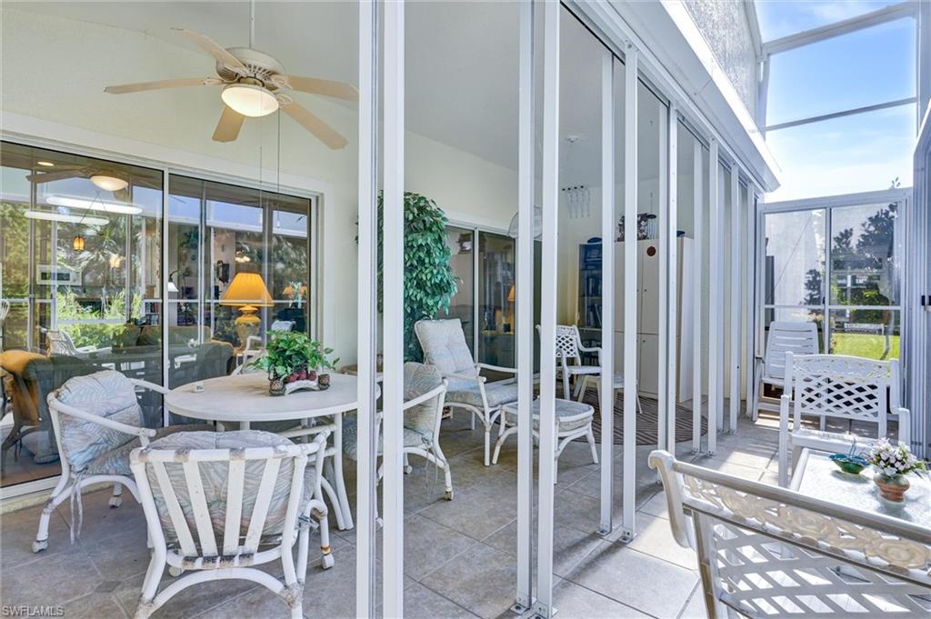 Screened lanai featuring a ceiling fan with integrated lighting, tiled flooring, and a glass-paneled entry door