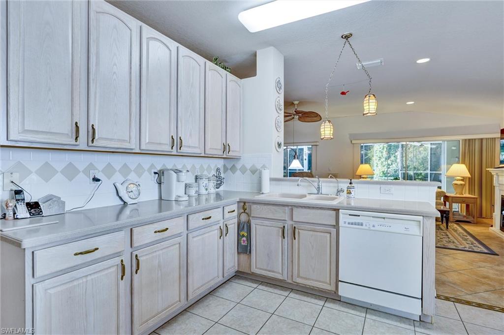Kitchen featuring light-toned cabinetry with brass hardware, a white tile backsplash with decorative accents, and light-colored countertops