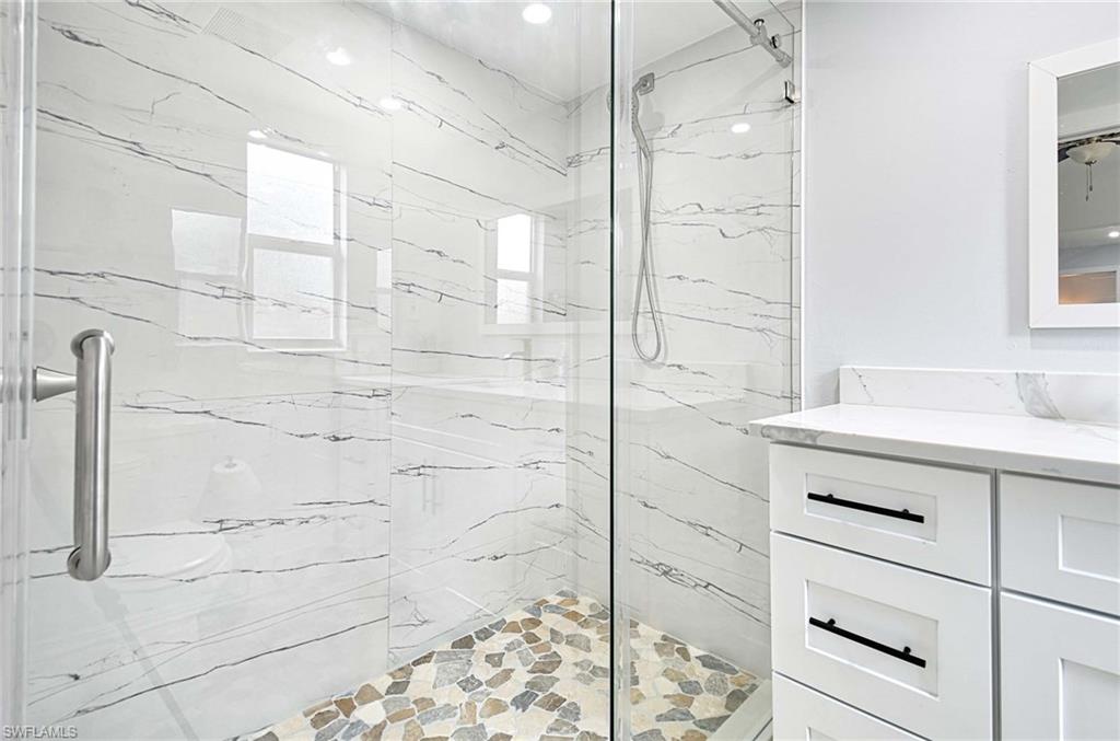 Bathroom featuring vanity and a marble finish shower