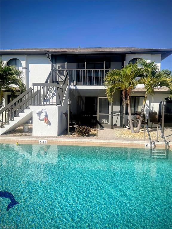 featuring stairs, a community pool, a patio area, and stucco siding