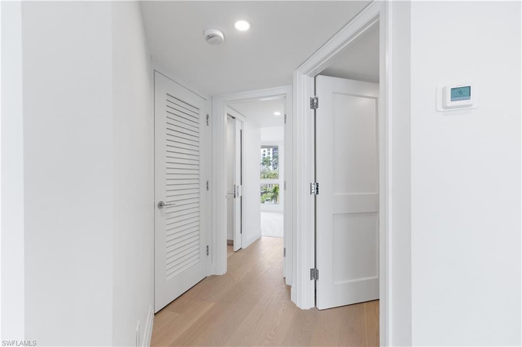 Hallway with light wood finished floors and recessed lighting