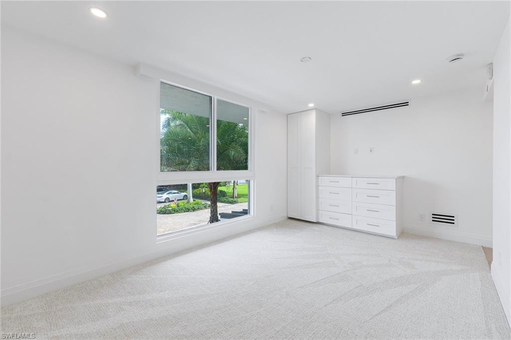 Unfurnished bedroom with light colored carpet and recessed lighting