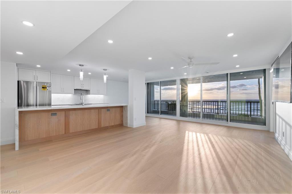 Kitchen with white cabinetry, open floor plan, expansive windows, freestanding refrigerator, and hanging light fixtures