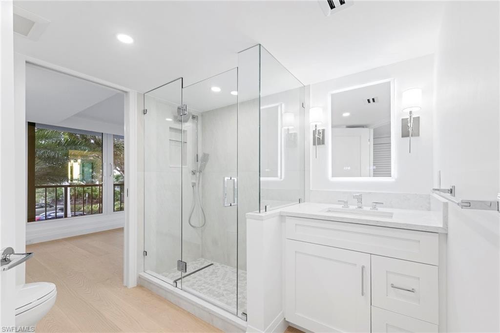 Bathroom with vanity, a shower stall, light wood-type flooring, and recessed lighting