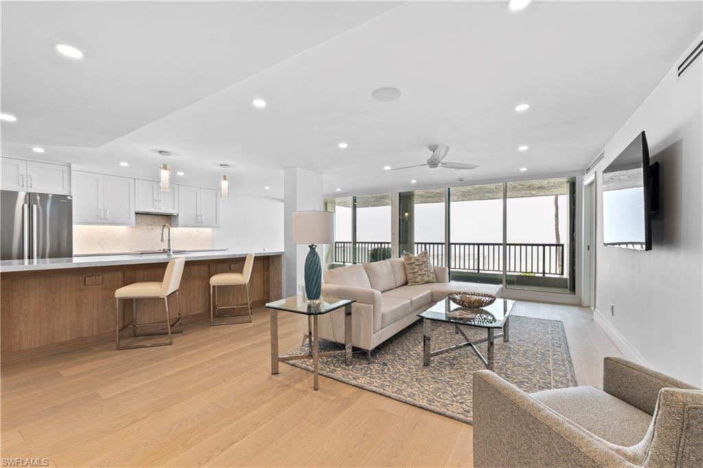 Living room featuring expansive windows, light wood finished floors, ceiling fan, and recessed lighting