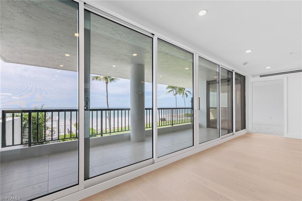 Doorway to outside with wood finished floors, plenty of natural light, a wall of windows, and a water view