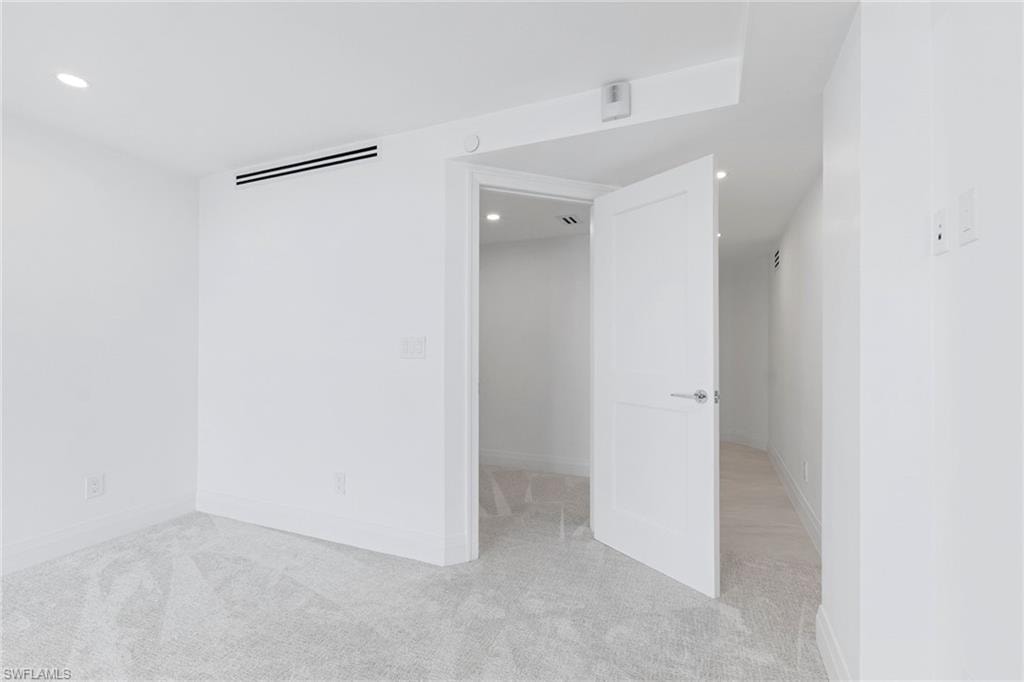 Unfurnished bedroom with light carpet and recessed lighting