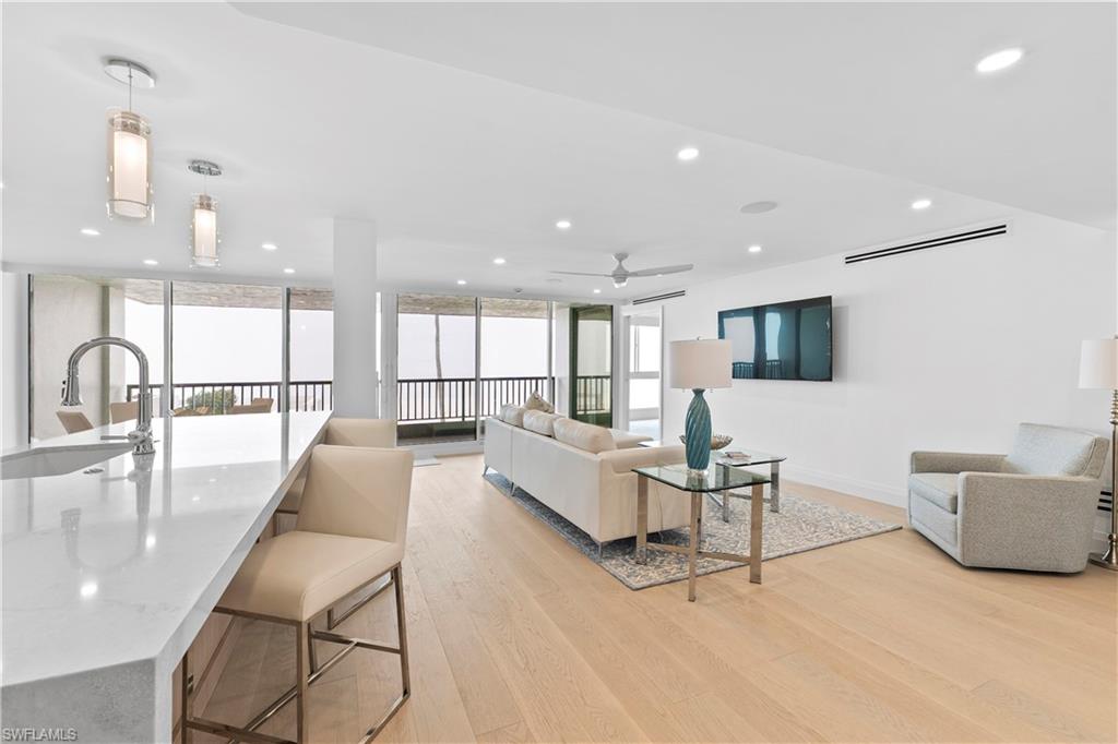 Living room with light wood-style floors, expansive windows, recessed lighting, and ceiling fan