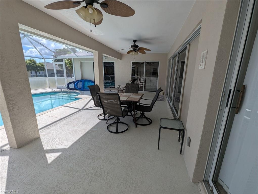 View of patio / terrace featuring a sunroom, a ceiling fan, an outdoor pool, a lanai, and outdoor dining area