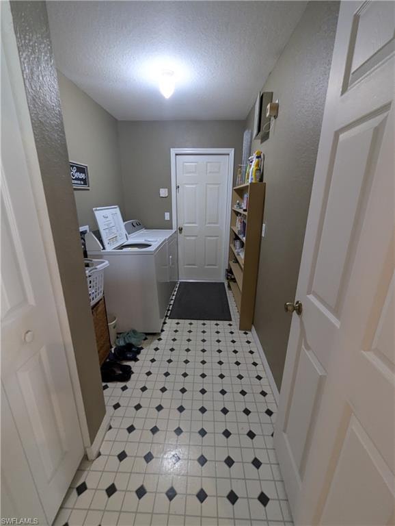 Washroom featuring washing machine and dryer, a textured ceiling, and light tile patterned floors