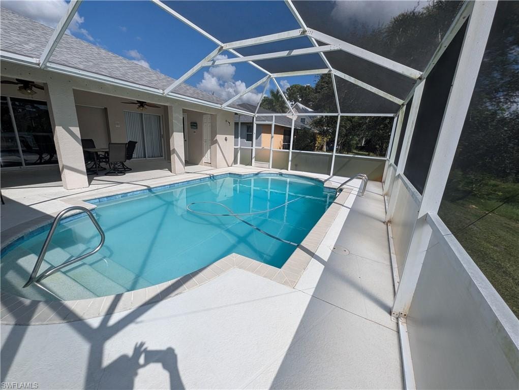 Outdoor pool with a sunroom, a lanai, a patio, and a ceiling fan