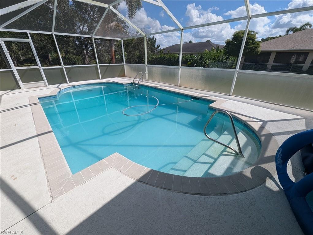Outdoor pool with glass enclosure, a sunroom, and a patio area