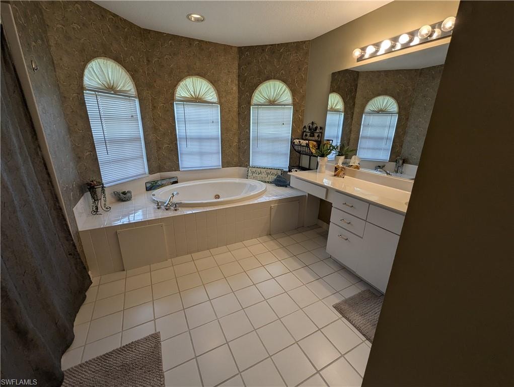 Bathroom with vanity, a whirlpool tub, light tile patterned flooring, plenty of natural light, and wallpapered walls