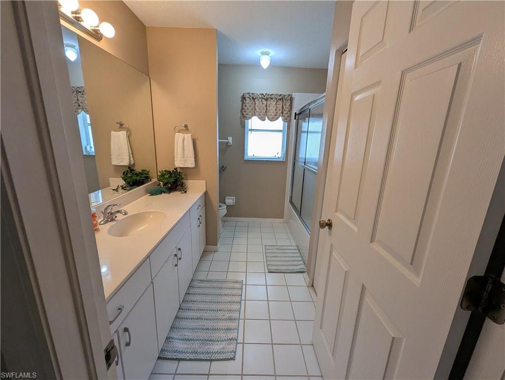 Bathroom featuring vanity, light tile patterned floors, and enclosed tub / shower combo