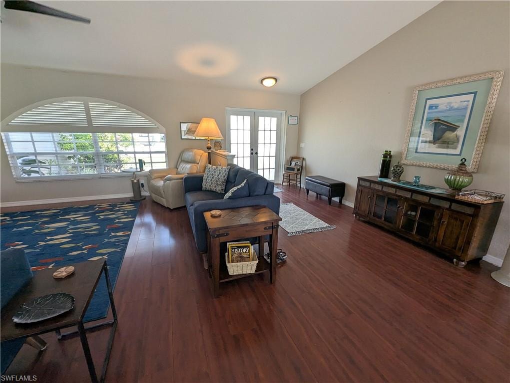 Living area with vaulted ceiling, french doors, and dark wood-style flooring