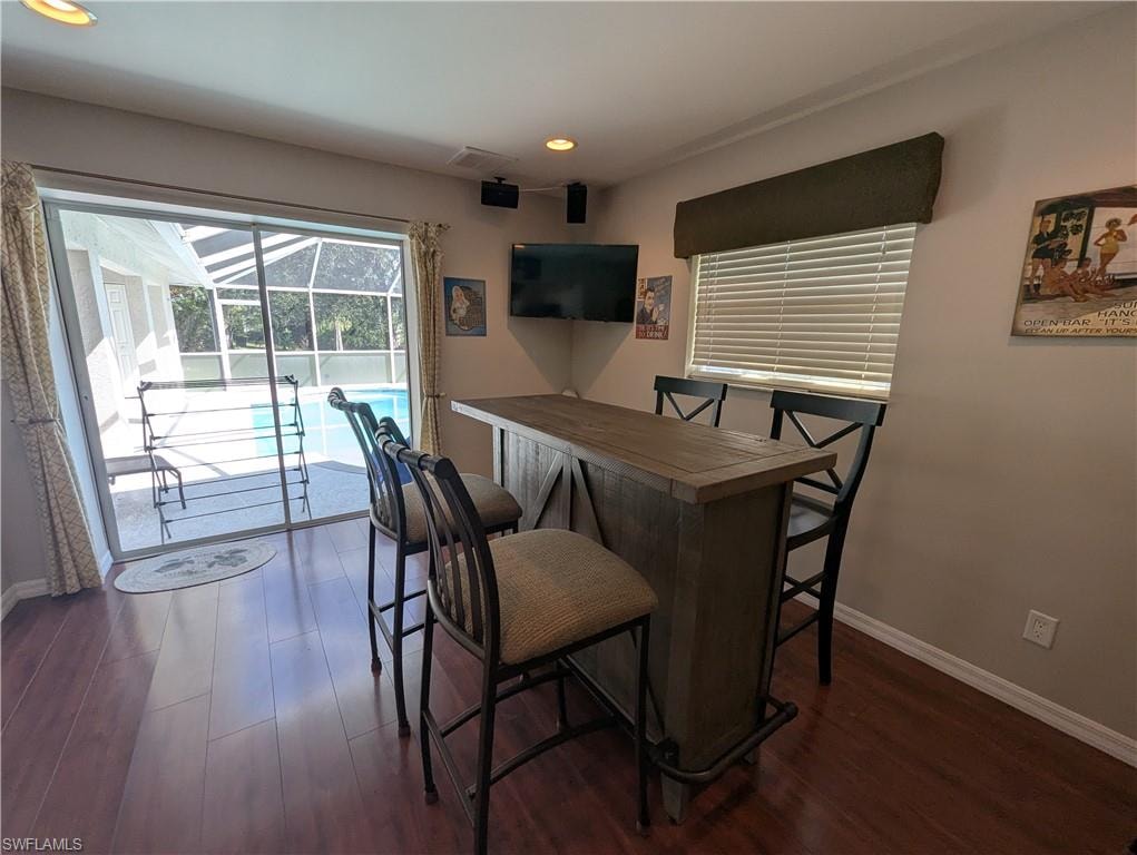 Bar area with dark wood finished floors, recessed lighting, a sunroom, and wood counters