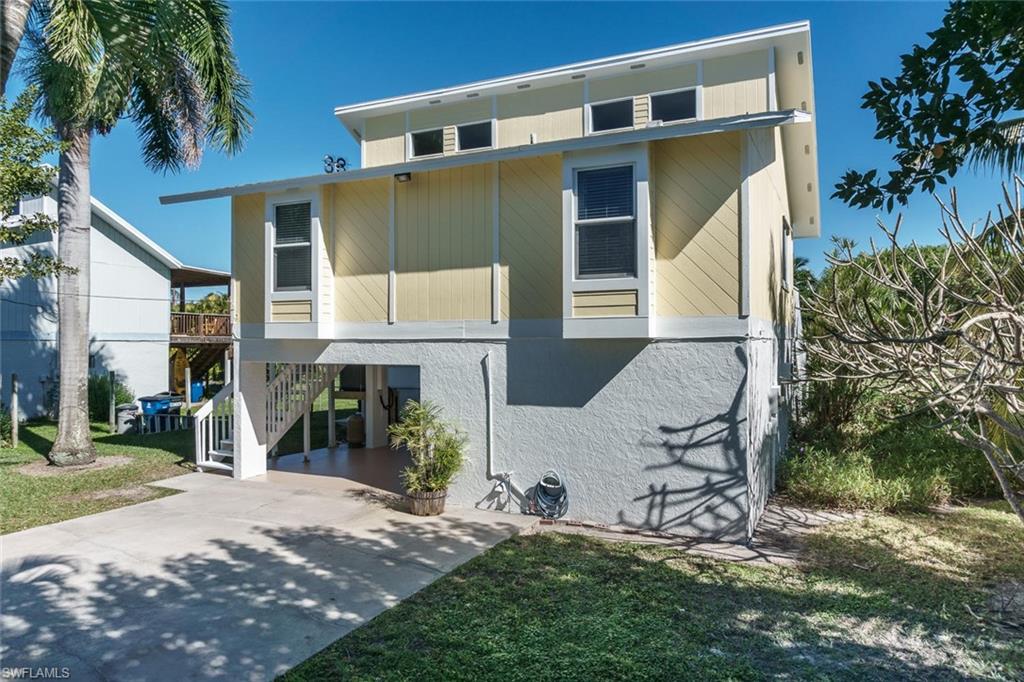 View of front of home with a carport, stairway, driveway, a balcony, and a front yard