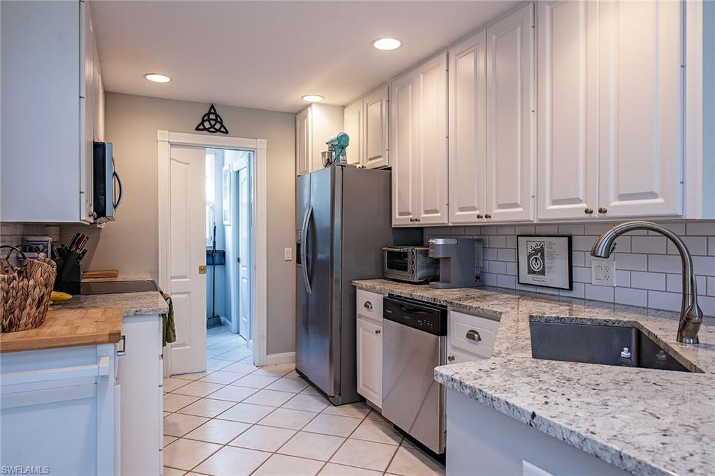 Kitchen with backsplash, white cabinets, stainless steel appliances.