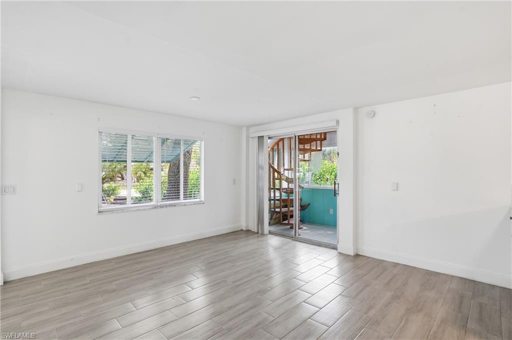 Bright interior space featuring neutral wall tones, wood-finish flooring, and a multi-pane window with horizontal blinds - Virtually Edited Image