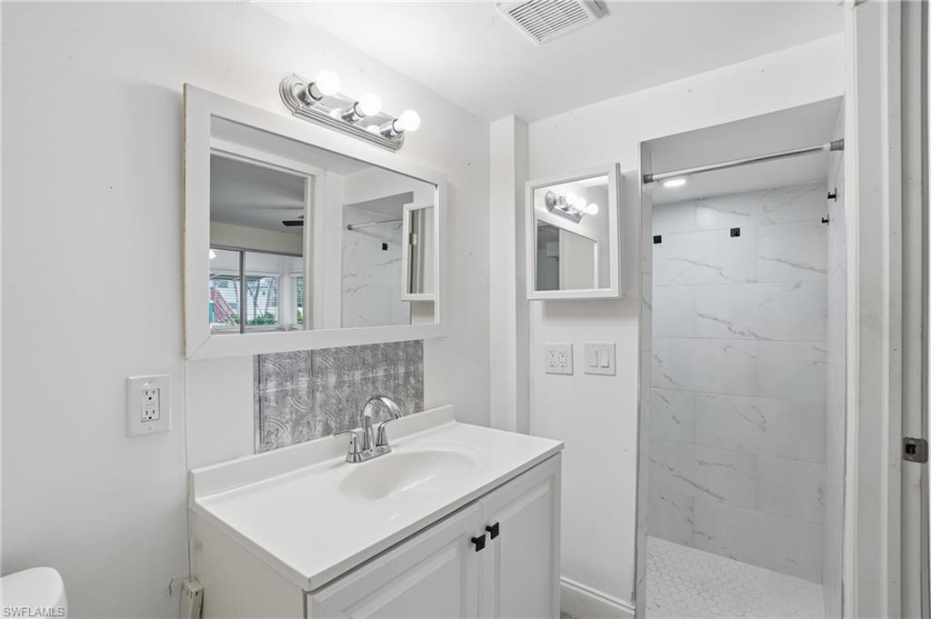 Bathroom featuring a white vanity with integrated sink, chrome faucet, and overhead vanity lighting - Virtually Edited Image