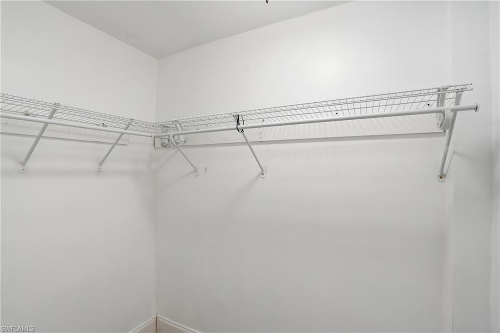 Corner closet storage featuring white wire shelving and hanging rods, providing organized space - Virtually Edited Image