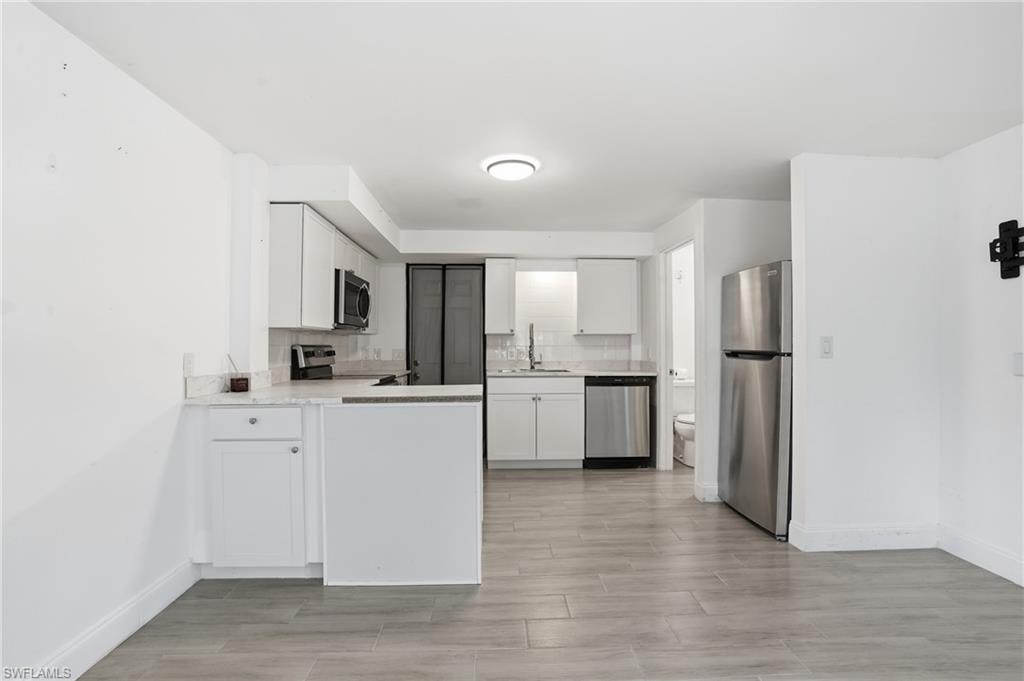 Kitchen area featuring white cabinetry, light-toned countertops, and stainless steel appliances - Virtually Edited Image