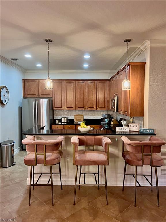 Kitchen with kitchen peninsula, a kitchen breakfast bar, decorative light fixtures, and appliances with stainless steel finishes