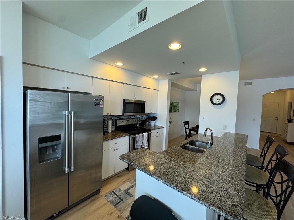 Kitchen with light wood-type flooring, white cabinetry, sink, and stainless steel appliances